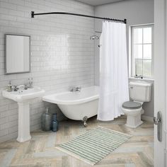 a bathroom with two sinks, a toilet and a bathtub in white tile on the floor