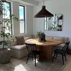 a living room filled with furniture and a wooden table surrounded by potted plants on top of a rug