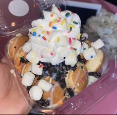 a plastic container filled with donuts covered in frosting and sprinkles