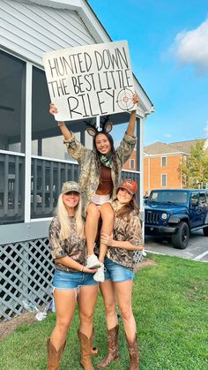 three women standing in front of a building holding up a sign that says, hunting down the best little bitty