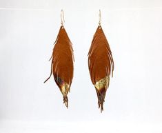 A beautiful fun pair of earrings, these are made using the finest quality soft natural tan leather with gold leaf tips.They are so light and soft, you will barely know that you are even wearing earrings.  The color is the perfect accent to any outfit and is incredibly versatile.  The gold simply pops from the brown background that gives a stunning iridescence when they swivel!They measure approximately 4 inches in length.  The earring hooks are gold plated.If you would like a different size, ple Adjustable Gold Feather Earrings, Leather Feather Earrings, Brown Background, Natural Tan, Leather Fringe, Etsy Earrings Dangle, Feather Earrings, Fringe Earrings, Earrings Photo