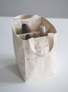 a tote bag with two bottles in it on a white table next to some pens and pencils