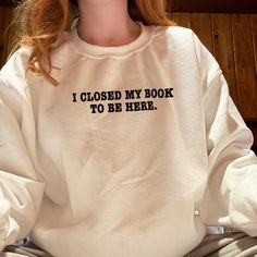 a woman wearing a sweatshirt that says i closed my book to be here