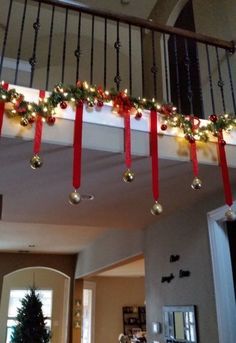 christmas decorations are hanging from the banisters in front of a house's staircase