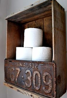 an old wooden box with some rolls of toilet paper in it on top of a shelf