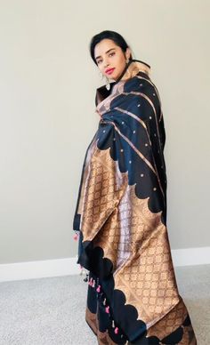 This stunning black 100% Mulberry Katan silk saree is handwoven in Banaras, known for its intricate designs and high-quality craftsmanship. The saree features a beautiful shade of black body and Meenadar flowers on the body with golden zari work, creating a mesmerizing effect. The body and palla has the kadbaan design depicting the pillars and corridors of the old historical palaces . The saree is perfect for any special occasion, such as a wedding, festival, or formal event. Comes finished with Elegant Black Shawl With Zari Work, Elegant Black Traditional Wear For Ceremonial Occasions, Black Katan Silk Saree With Cutdana, Black Katan Silk Saree With Cutdana Details, Anarkali Black Silk Dupatta, Black Silk Anarkali Dupatta, Elegant Black Pashmina Shawl With Traditional Patterns, Elegant Black Saree For Eid, Elegant Black Shawl With Traditional Patterns