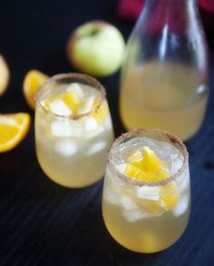 two glasses filled with drinks sitting next to an apple