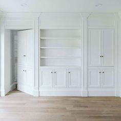 an empty room with white walls and wooden floors, built in shelving unit on the far wall