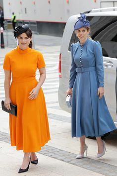 two women standing next to each other in front of a white van and one wearing an orange dress