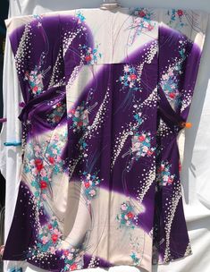 Japanese genuine kimono, purple, pale lavender and white crepe, printed with colourful floral bouquets and white plum blossoms, as well as flower carriages. The kimono is furisode style with long sleeves, which is worn by young single women in Japan. It is in excellent condition and only a small faint stain at the fold at the back of collar and a couple small ones on the upper lining indicate prior wear. Measurement armpit to armpit is 25 inches, sleeve edge to sleeve edge 52.5 inches, length of sleeves is 41 inches, and the length from the nape of the neck to hem is 63.5 inches. Traditional White Floral Print Kimono, Traditional White Floral Kimono, Purple Floral Print Kimono For Spring, Spring Purple Floral Print Kimono, Long Purple Kimono For Spring, Purple Floral Print Kimono With Kimono Sleeves, White Plum, Plum Blossoms, Pale Lavender