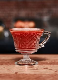 a glass cup filled with liquid sitting on top of a wooden table