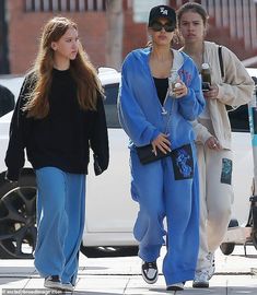 two women walking down the street with one holding a drink