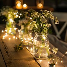 several mason jars filled with flowers and fairy lights are lined up on a wooden table