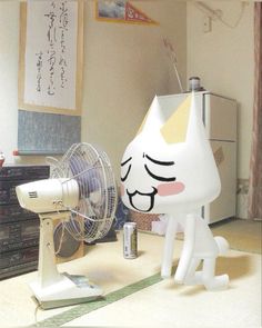 a white cat sitting on top of a table next to a fan