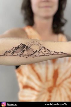 a woman with a mountain tattoo on her arm