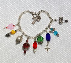 This Fruit of the Spirit Bracelet is handmade using a variety of unique charms, beads, and chain.  One size fits all - easy to adjust clasp.  Beads includes treasures from my mother's old necklaces.  Each bracelet is one-of-a-kind. Spiritual Metal Rosary Bracelet As Gift, Czech Glass Bracelets With Lobster Clasp As Gift, Spiritual Beaded Bracelets With Lobster Clasp As Gift, Charm Bracelet With Colorful Beads For Gift, Spiritual Beaded Bracelets With Lobster Clasp, Multicolor Beaded Metal Charm Bracelet, Gift Bracelets With Dangling Round Beads Charms, Spiritual Metal Beaded Bracelets For Gifts, Multicolor Charm Bracelet With Heart Beads As A Gift