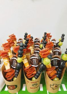 football snacks are arranged in cones on a green tray with white and black striped tablecloth