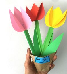 a hand holding a paper vase with flowers in it