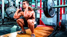 a man is squatting in the gym with his hands on his hips and holding a barbell