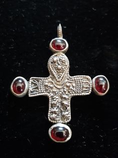 a silver cross with two red stones on it