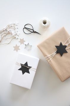 two wrapped presents with black and white stars on them next to scissors, twine and string