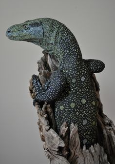 a lizard statue sitting on top of a tree stump