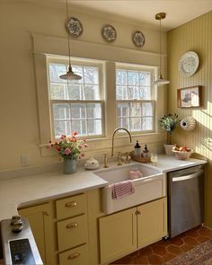 a kitchen with yellow cabinets and white counter tops is pictured in this image, there are plates hanging on the wall above the sink