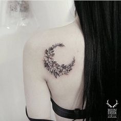 a woman's shoulder with a flowered crescent tattoo on it