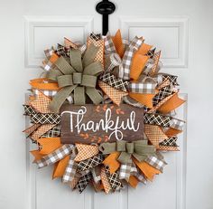 a wreath with the words, thank you on it hanging on a white front door