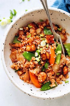 a bowl filled with rice and vegetables on top of a white tablecloth next to a blue towel