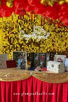 the table is set up with red and gold decorations on it, along with photos