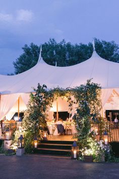 an outdoor tent set up with candles and greenery