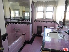 a bathroom with pink tiles and black trim around the bathtub, sink, and mirror