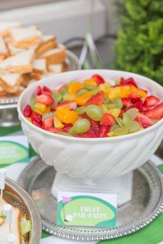 fruit salad in a white bowl on a silver platter with crackers and strawberries