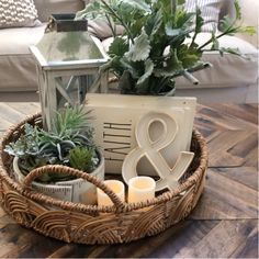 a basket filled with plants and candles on top of a wooden table next to a couch