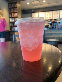 a pink drink sitting on top of a wooden table