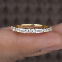 a woman's hand holding a gold and white diamond ring