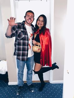 a man standing next to a woman wearing a red cape and holding a wicker basket