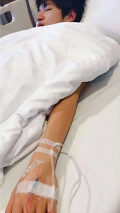 a person laying in a hospital bed with an iv attached to their arm and hand