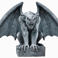 a statue of a demon sitting on top of a stone block with its wings spread