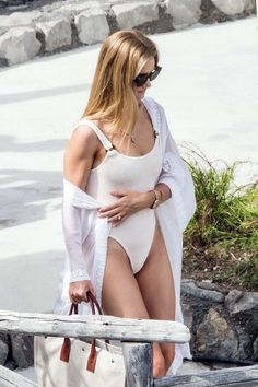 a woman in a white swimsuit is walking down the stairs with her hand on her hip