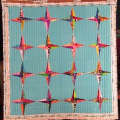 a quilted wall hanging with many colorful stars on it