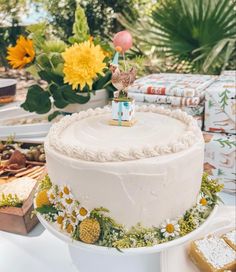 a white cake sitting on top of a table covered in flowers and other food items