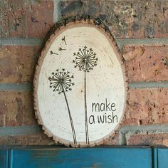 a piece of wood that says make a wish on it with dandelions in the center