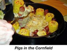 a skillet with corn on the cob and hot dogs in it, ready to be eaten