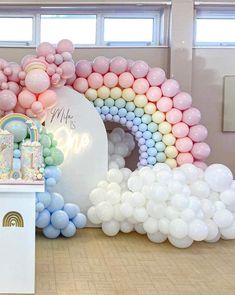 an arch made out of balloons and pastel colors is on display at a birthday party