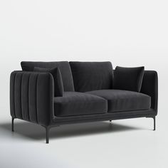 a black couch with two pillows on top of it and one arm extended to the side