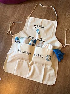 an apron with the words daddy's new toothbrushes in it is sitting on a wooden floor