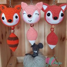 three crocheted animals hanging from chains in a wooden box with balls of yarn