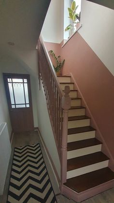 the stairs are painted pink and white with black and white chevron rug on the floor